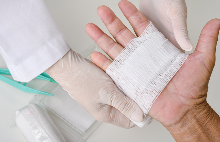 Assessment and Treatment of Wounds A gloved hand applies a bandage to a patient's open palm.