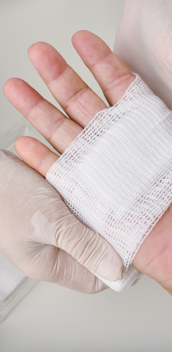Wound Care Training A hand with a white bandage being held by another gloved hand.