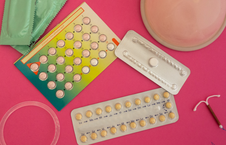 Assorted contraceptive methods including pills, a diaphragm, and an IUD on a pink background.