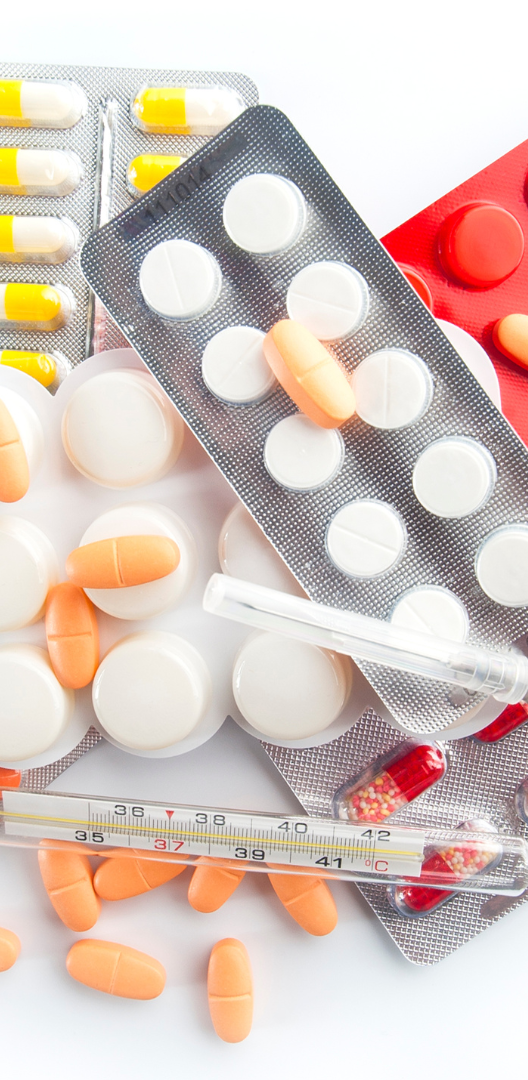Assorted medications including tablets, capsules, and a thermometer on a white background.