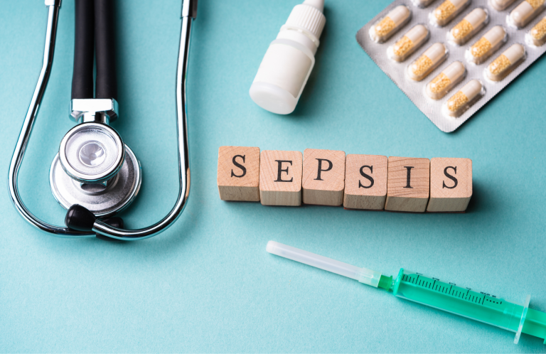 Sepsis Awareness Training Stethoscope, syringe, pill packet, and wooden blocks spelling "SEPSIS" on a teal background.