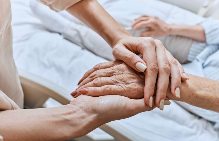 End of Life Care A younger person's hand gently holding an older person's hand.