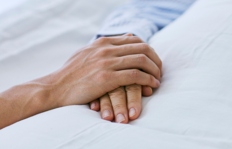 A gloved hand holding a flexible rubber catheter on a medical surface.
