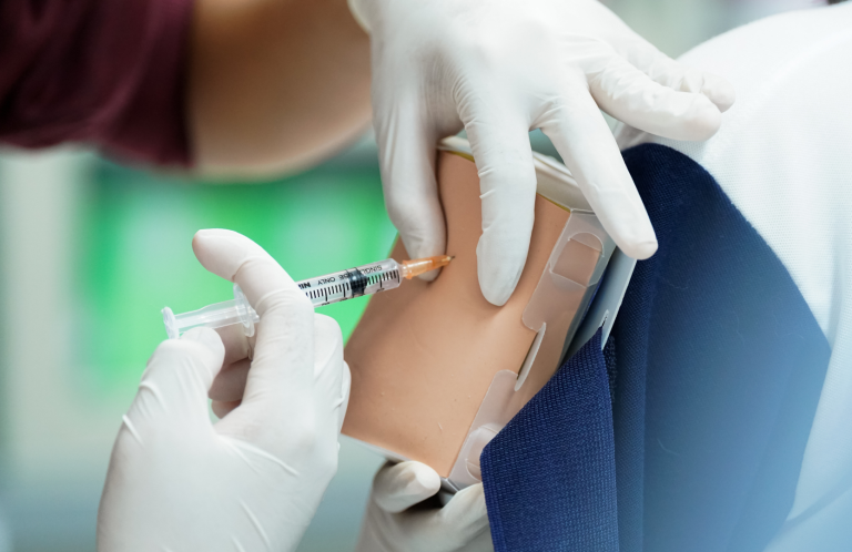 A healthcare professional administering an injection to a training model.