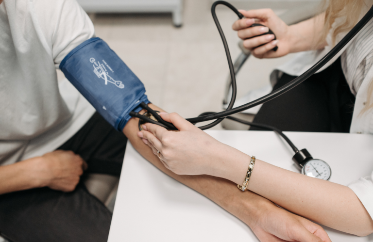 A healthcare worker cleans a table in a hospital setting while patients are treated nearby.