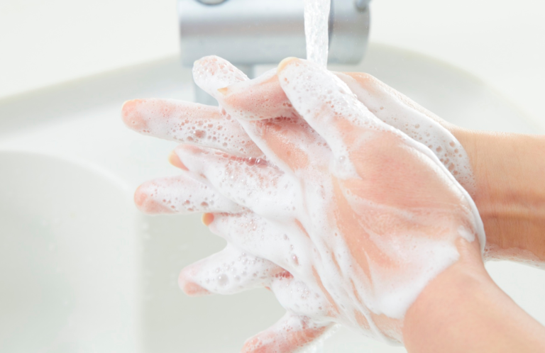 Hands lathered with soap under running water at a sink.