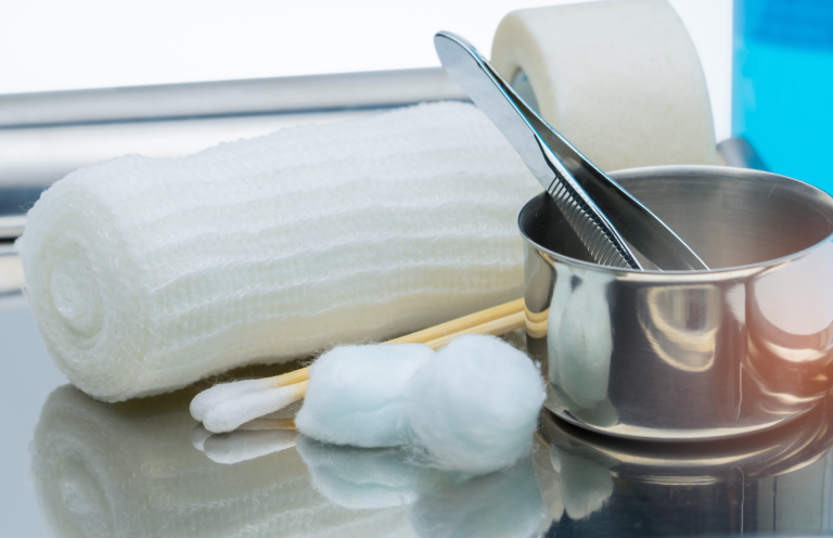 First aid supplies including bandages, cotton balls, and metal tools on a surface.