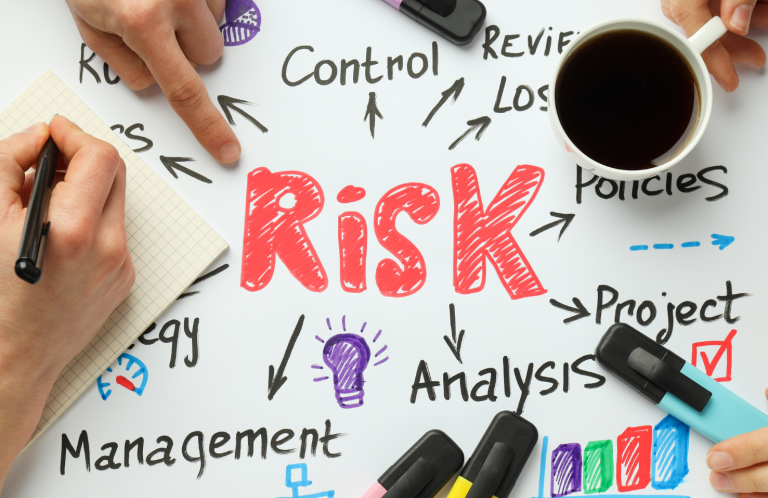 Clinical Risk Assessment Training Hand pointing at the word "RISK" with related concepts and a cup of coffee nearby.