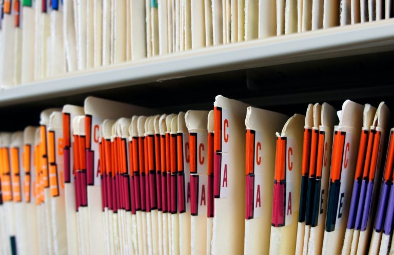 File folders organised on a shelf, with colour-coded labels for easy identification.