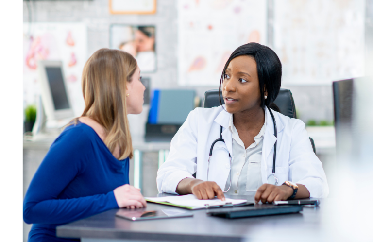 A doctor in a white coat discusses health matters with a patient in an office.
