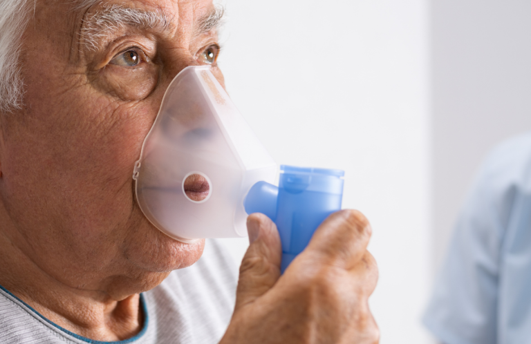 Elderly man using a nebuliser for respiratory treatment.