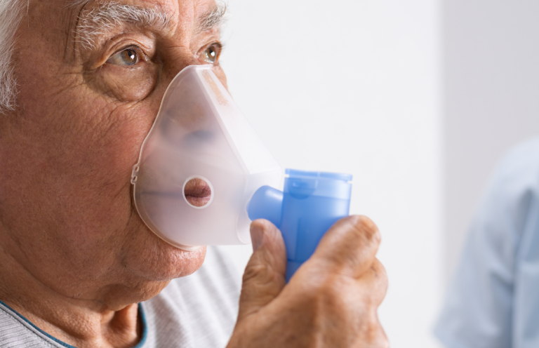 Elderly man using a nebuliser for respiratory treatment.