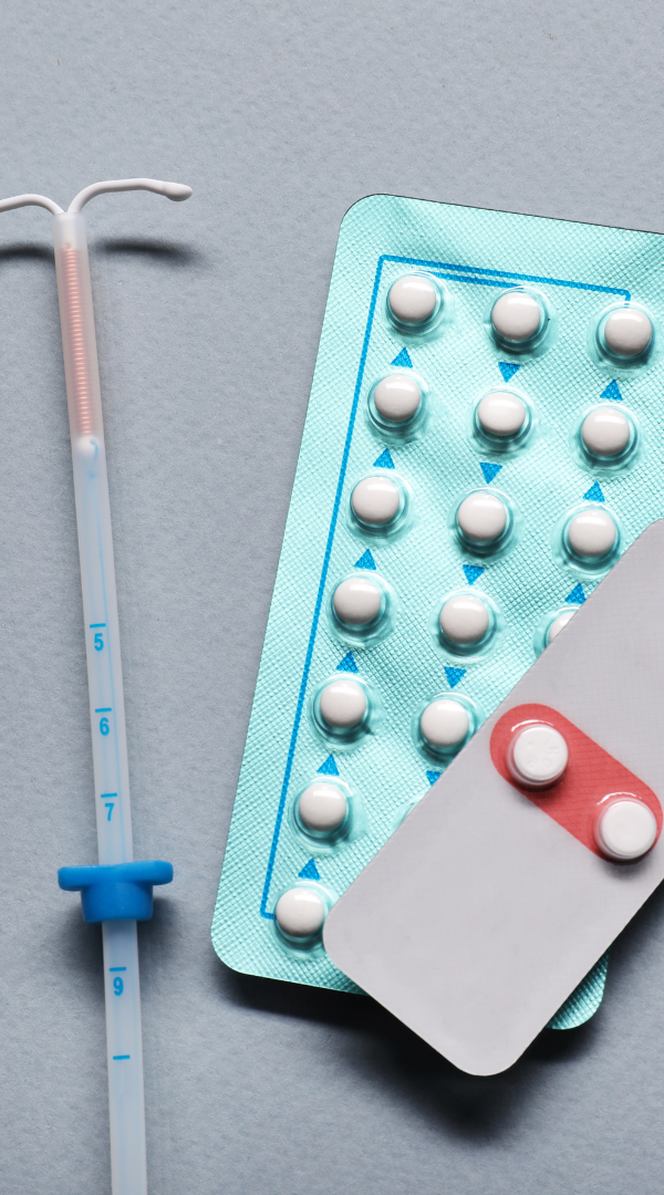 Contraception Update Contraceptive pills in packaging with an IUD device beside them.