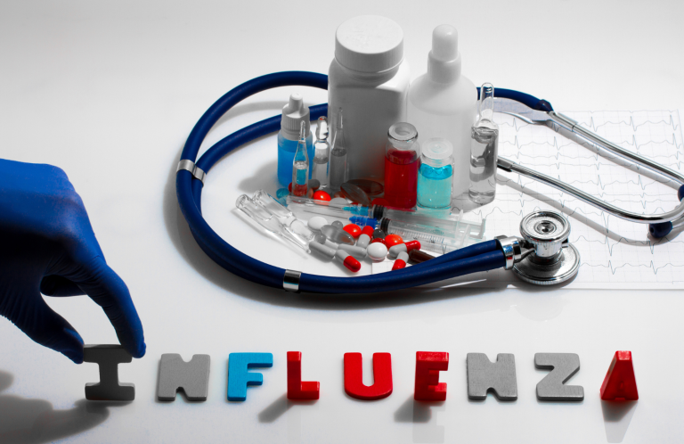 A stethoscope, medicine bottles, and letters spelling "INFLUENZA" on a table.