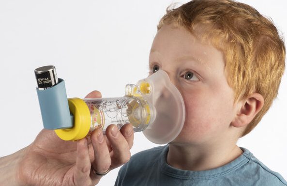 A boy using a spirometer for a lung function test in a medical setting.