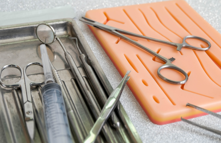 Basic Wound Care A tray of medical instruments including scissors, forceps, and a syringe.
