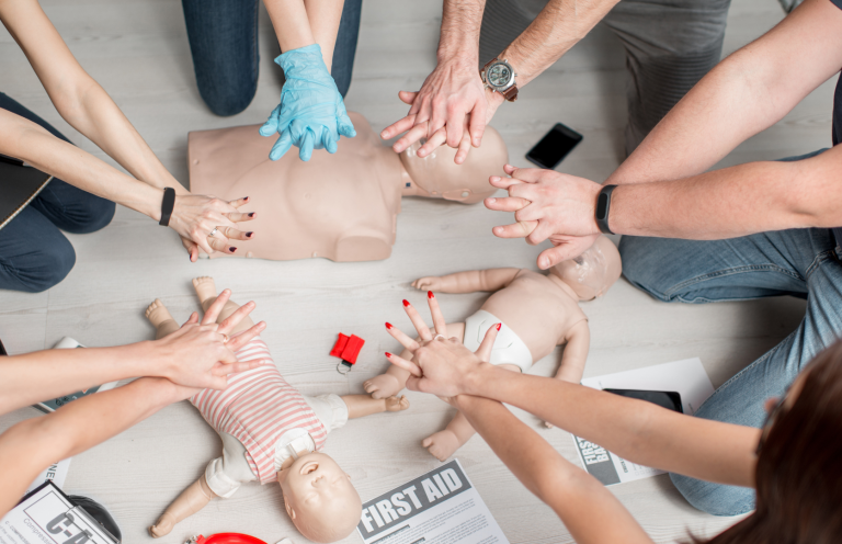 Basic Life Support and Anaphylaxis Update Hands performing CPR on infant mannequins during a training session.