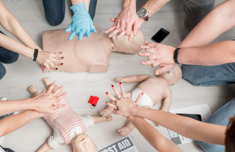 Basic Life Support Training Multiple hands performing CPR on training mannequins in a training session.