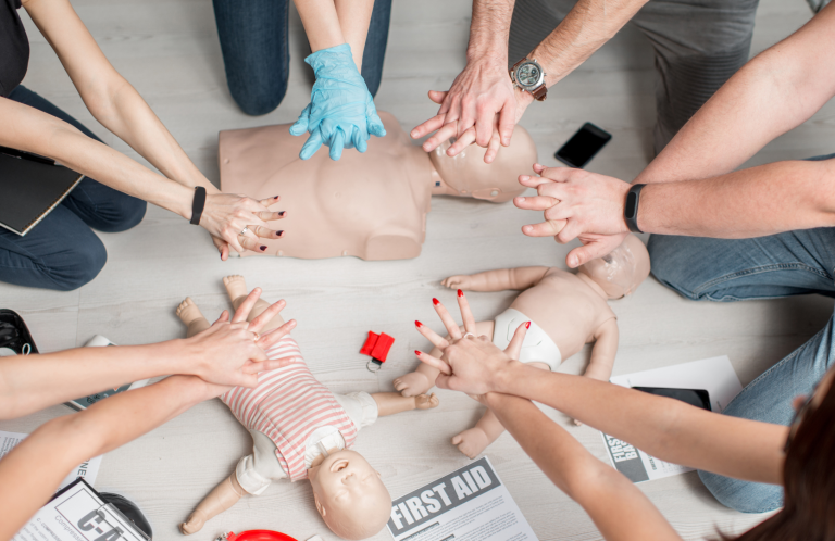 Hands demonstrating CPR techniques on infant mannequins during a training session.