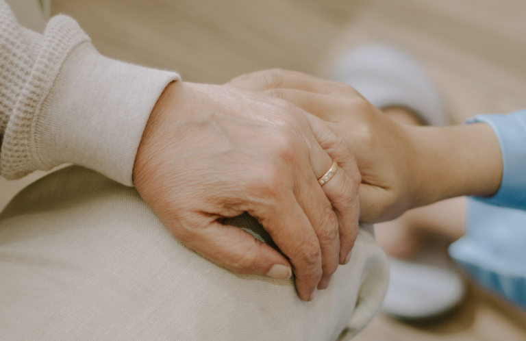 Two hands clasped together, one wearing a ring, symbolising connection and support.