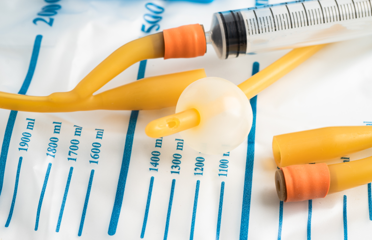 Catheterisation for Registered Practitioners Medical tubing and a syringe on a measurement-printed surface.