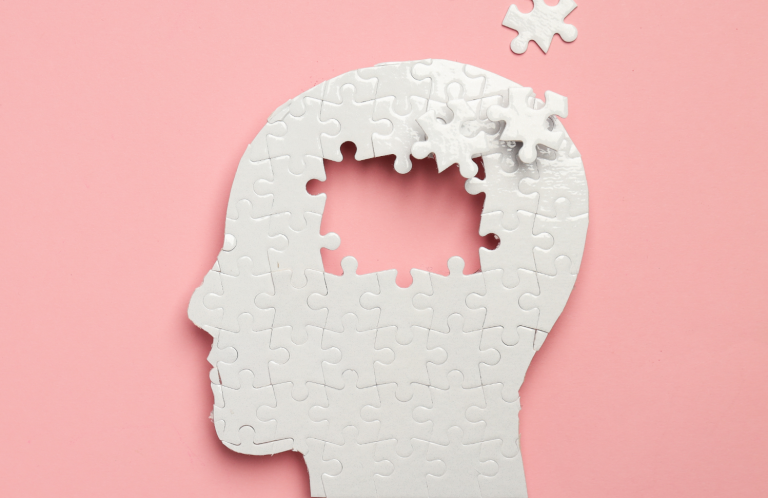 A silhouette of a head with puzzle pieces missing against a pink background.