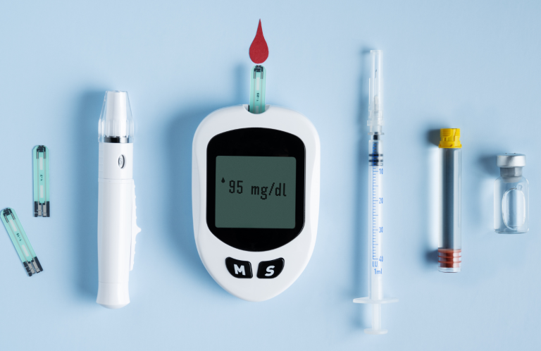 Diabetes testing supplies including a glucose meter, test strips, and syringes on a blue background.