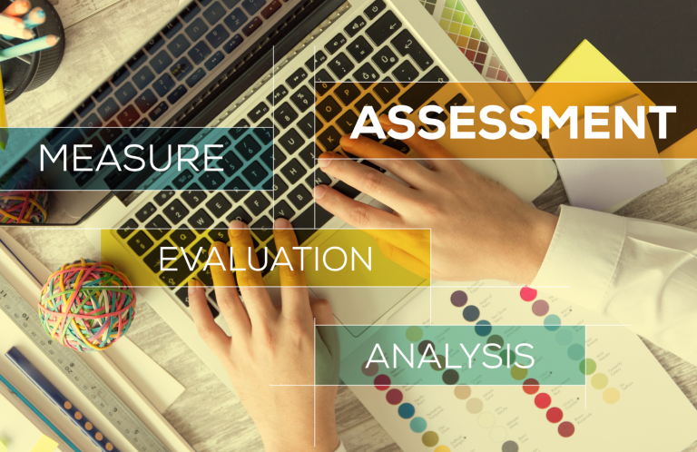 Hands on a keyboard surrounded by colourful items and text labels related to analysis and assessment.