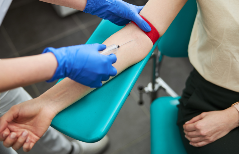 A healthcare professional draws blood from a patient's arm.