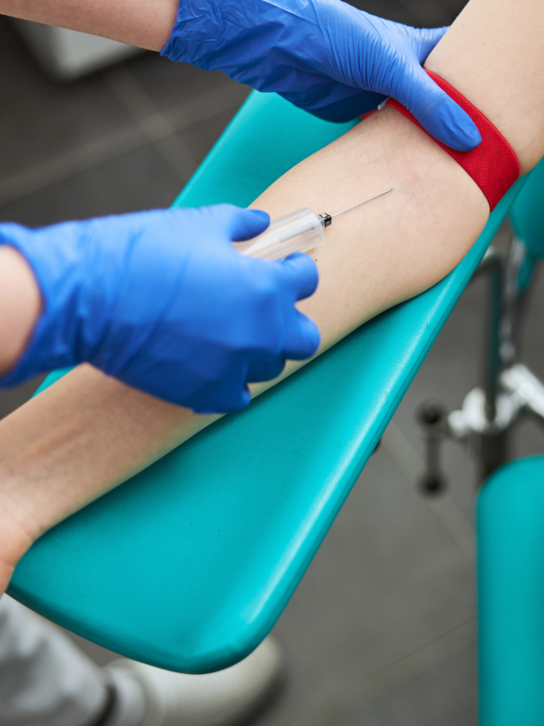 A healthcare professional preparing to extract blood from a patient's arm.